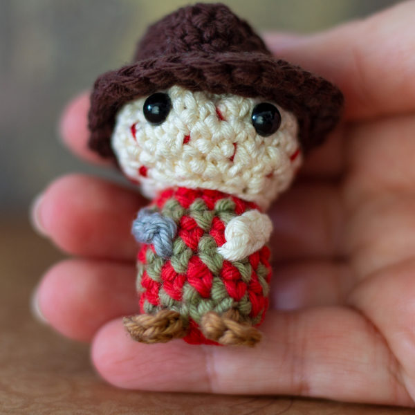 Amigurumi, figurines en crochet tenu dans une main représentant Freddy Krueger, imaginé et confectionné à la main par les Mignonstres, une marque le Rat et l’Ours.