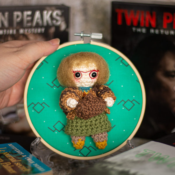 Tableau avec un amigurumi, figurine en crochet, représentant Log lady, de la série Twin Peaks, tenu en main, imaginé et confectionné à la main par le Rat et l'Ours.