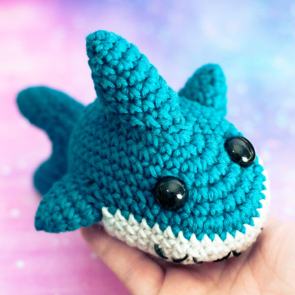 Amigurumi, figurines en crochet représentant un requin mignon,tenu en main imaginé et confectionné à la main par les Mignonstres, une marque le Rat et l’Ours.