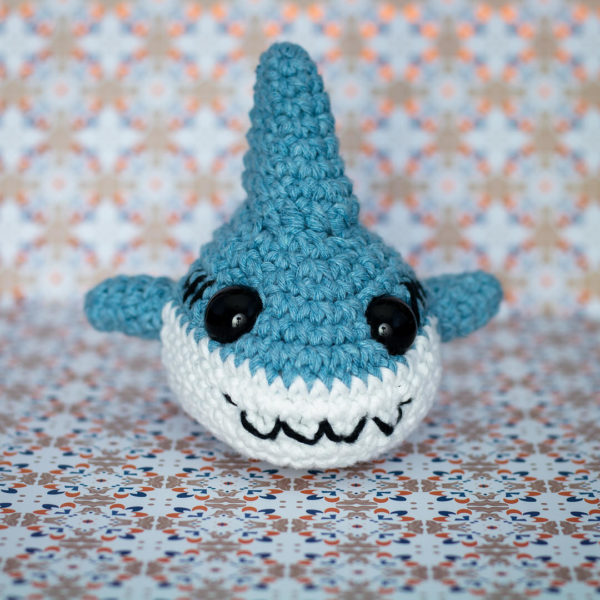 Peluche amigurumi, figurine en crochet, représentant un requin de face, imaginé et confectionné à la main par le Rat et l'Ours.