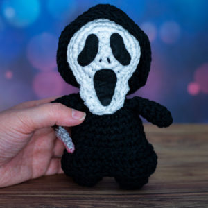 Amigurumi, figurine en crochet représentant Ghostface de la franchise Scream, tenu en main imaginé et confectionné à la main par les Mignonstres, une marque le Rat et l’Ours.