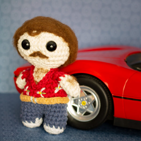 Amigurumi, figurine en crochet représentant Thomas Magnum et sa célèbre Ferrari, de profil, imaginé et confectionné à la main par les Mignonstres, une marque le Rat et l’Ours.