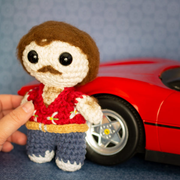 Amigurumi, figurine en crochet représentant Thomas Magnum et sa célèbre Ferrari, tenu en main, imaginé et confectionné à la main par les Mignonstres, une marque le Rat et l’Ours.