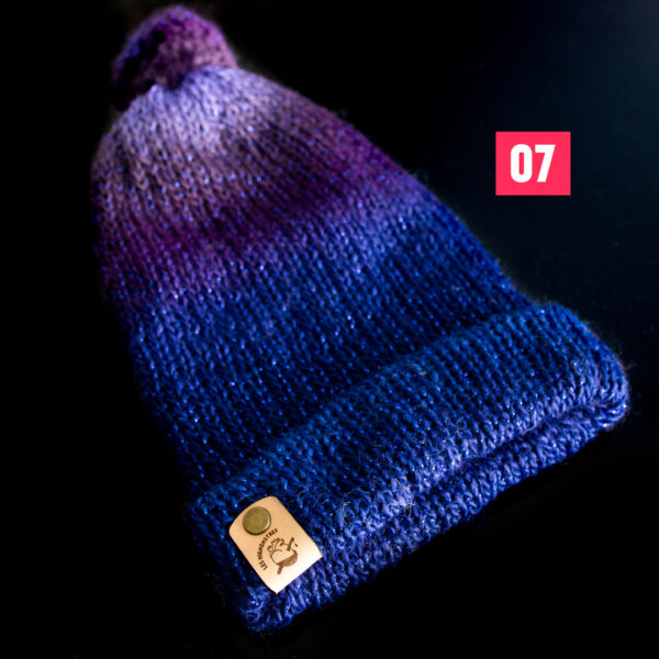 Bonnets en tricot, dans les tons violet et bleu, avec un fil pailleté, imaginé et confectionné à la main par les Mignonstres, une marque le Rat et l’Ours.