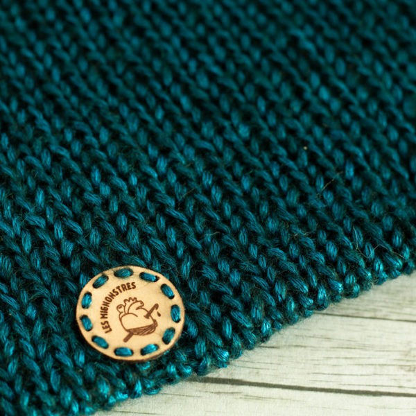 Bonnets en tricot, porté par une femme représentant des oreilles de chat bleus, imaginé et confectionné à la main par les Mignonstres, une marque le Rat et l’Ours.