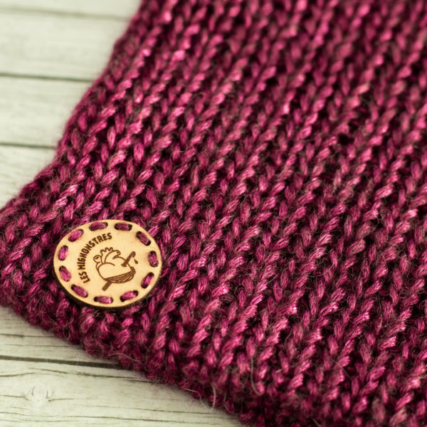 Bonnets en tricot, porté par une femme représentant des oreilles de chat roses, imaginé et confectionné à la main par les Mignonstres, une marque le Rat et l’Ours.