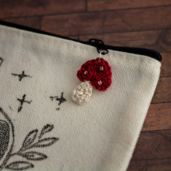 Détails d'une trousse en coton, linogravure par Celi-arts et ornement représentant un champignon rouge en crochet imaginé et confectionné à la main par les Mignonstres, une marque le Rat et l’Ours.