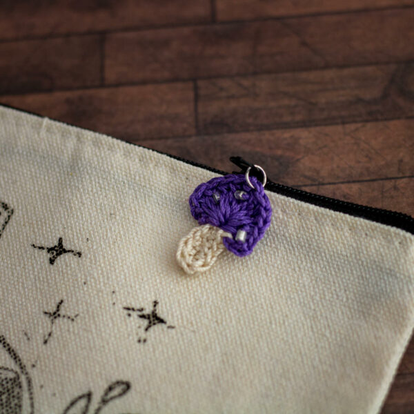 Détails d'une trousse en coton, linogravure par Celi-arts et ornement représentant un champignon violet en crochet imaginé et confectionné à la main par les Mignonstres, une marque le Rat et l’Ours.