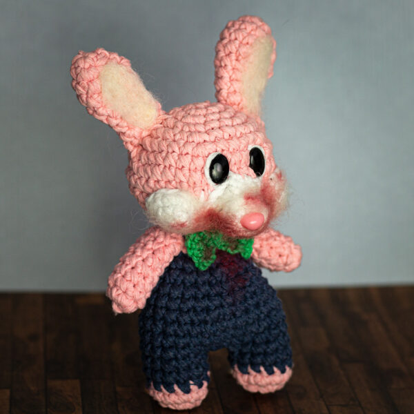 Amigurumi en crochet représentant Robbie le lapin, issu de la sage de jeu vidéo Silent Hill, de profil, imaginé et confectionné à la main par les Mignonstres, une marque le Rat et l’Ours.