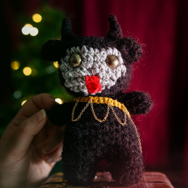 Amigurumi, figurine en crochet représentant Krampus, tenu en main, le monstre de Noël, imaginé et confectionné à la main par les Mignonstres, une marque le Rat et l’Ours.