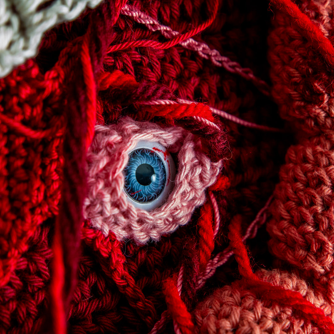 Détail d’un tableau en crochet sur le thème du body horror, avec des yeux, des dents, des instestins… Œuvre imaginée et confectionnée à la main par les Mignonstres, une marque le Rat et l’Ours.