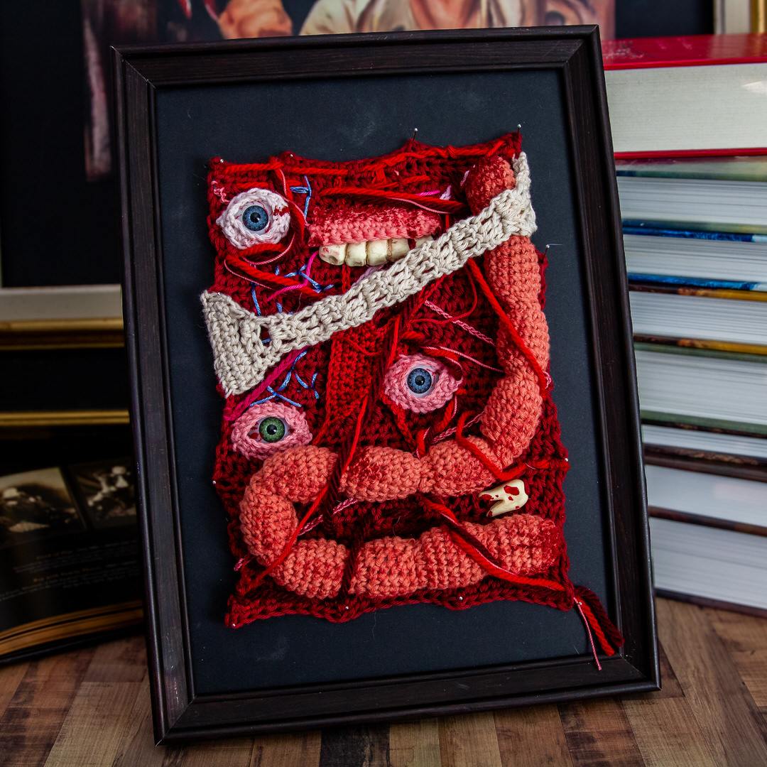 Tableau en crochet sur le thème du body horror, avec des yeux, des dents, des instestins… Œuvre imaginée et confectionnée à la main par les Mignonstres, une marque le Rat et l’Ours.