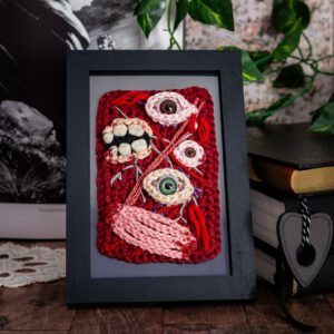Tableau en crochet sur le thème du body horror, avec des yeux, des dents, et des muscles comme un écorché… Œuvre imaginée et confectionnée à la main par les Mignonstres, une marque le Rat et l’Ours.