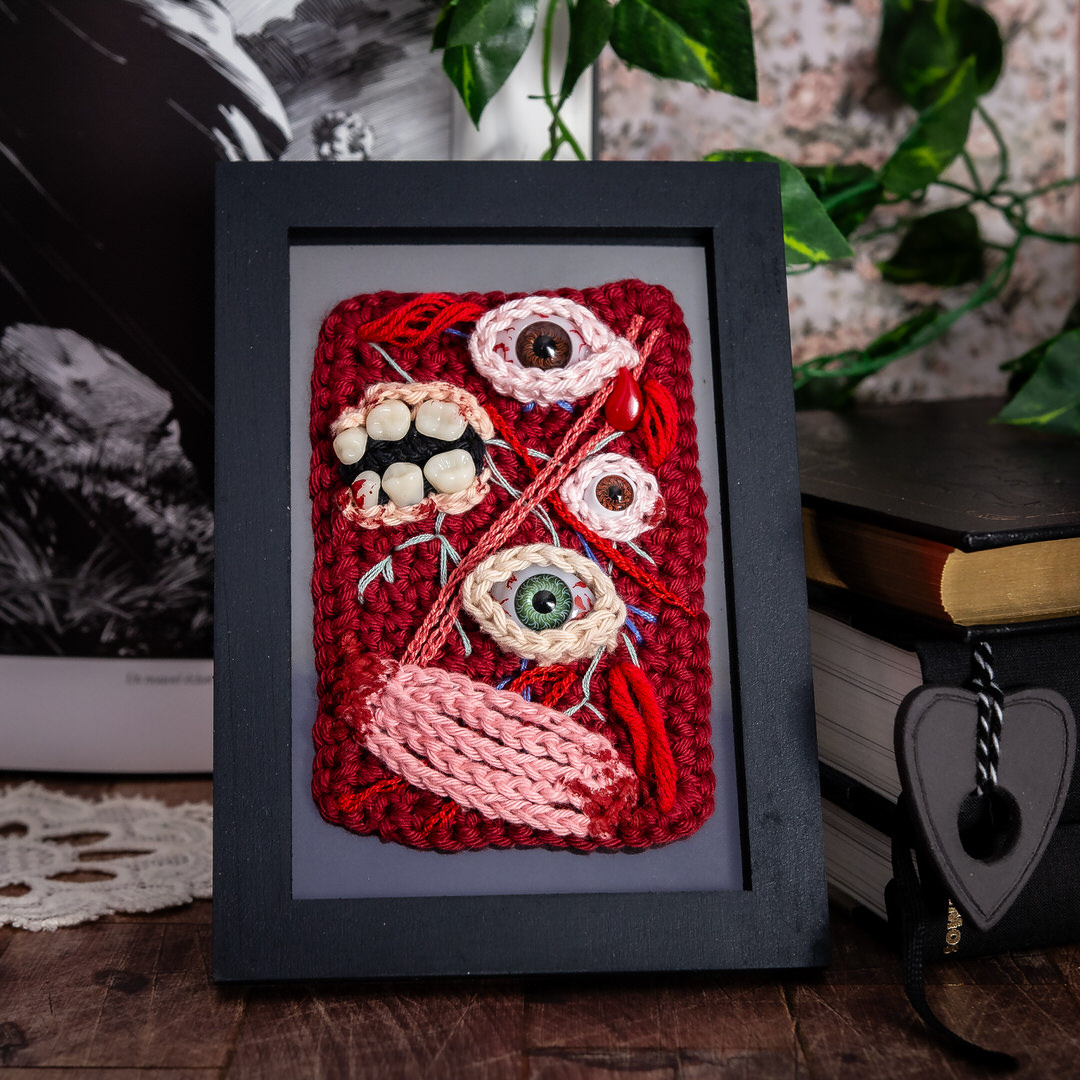 Tableau en crochet sur le thème du body horror, avec des yeux, des dents, et des muscles comme un écorché… Œuvre imaginée et confectionnée à la main par les Mignonstres, une marque le Rat et l’Ours.