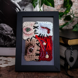 Tableau en crochet sur le thème du body horror, avec plusieurs peaux différentes cousues ensemble, comme un puzzle humain… Œuvre imaginée et confectionnée à la main par les Mignonstres, une marque le Rat et l’Ours.