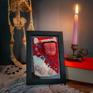 Tableau en crochet sur le thème du body horror, qui semble être un amas de chair et d'organes. Œuvre imaginée et confectionnée à la main par les Mignonstres, une marque le Rat et l’Ours.