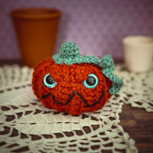 Amigurumi, figurines en crochet représentant une citrouille méchante avec yeux phosphorescents, imaginés et confectionnés à la main par les Mignonstres, une marque le Rat et l’Ours.